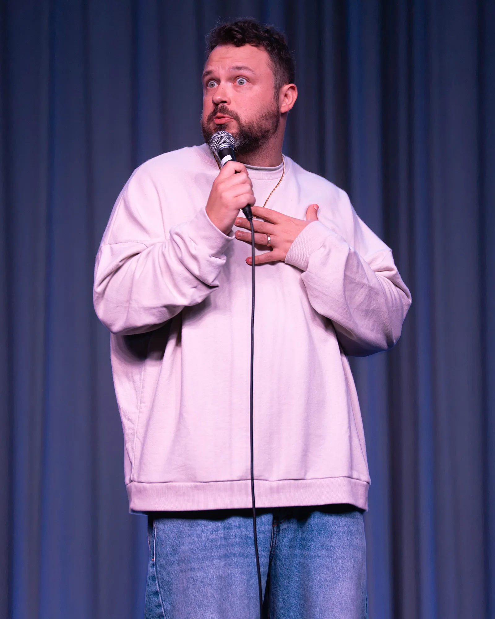 Ben Bankas holding a microphone during a stand-up performance in Charles Town, West Virginia