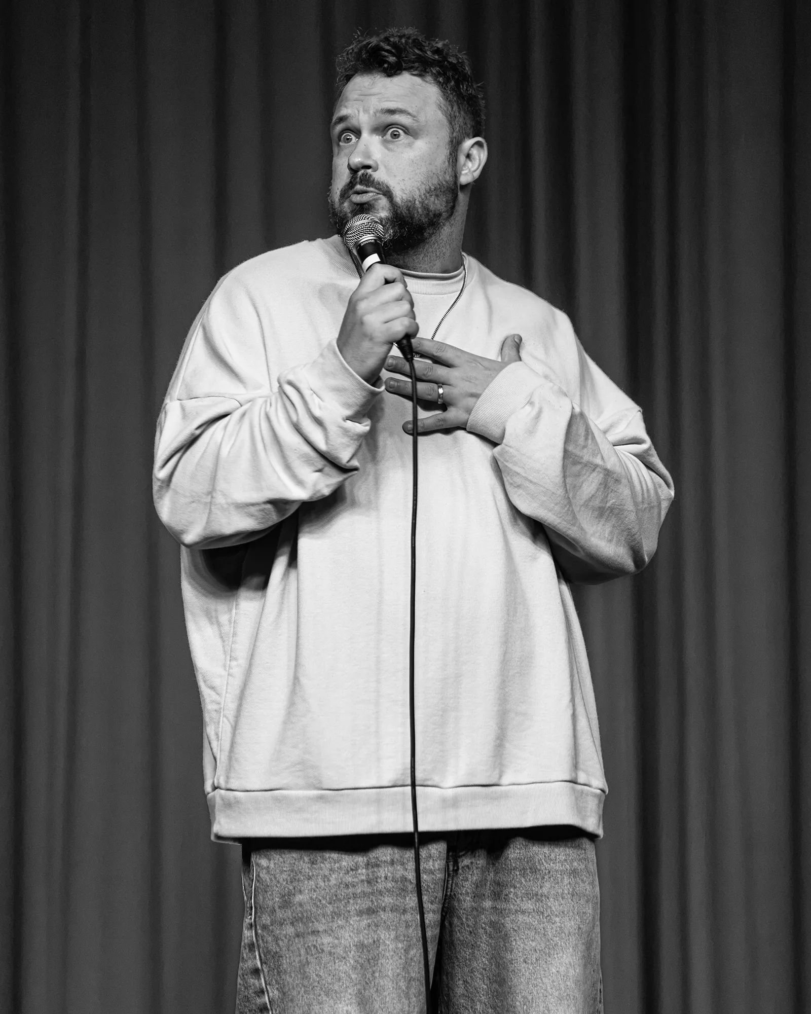 Ben Bankas performing with a microphone on stage in Charles Town, West Virginia